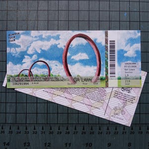 May include: A rectangular Summer Tour 2026 concert ticket featuring a blue sky with clouds and large red circular arches. The ticket displays text including GA LAWN, 07/17/2026, and a barcode. The lower portion shows a light pink geometric pattern.