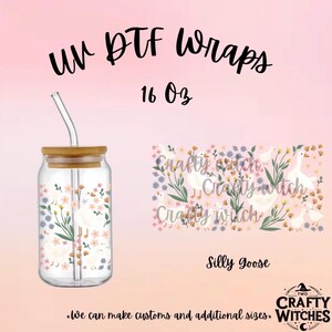 May include: A 16 oz glass tumbler with a bamboo lid and glass straw, featuring a UV DTF wrap with white geese, green foliage, and small pink and orange flowers. The text reads UV DTF Wraps, 16 Oz, Silly Goose, and Two Crafty Witches.