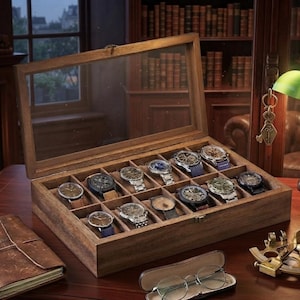 May include: A rectangular wooden watch display case with a hinged glass lid, featuring twelve individual compartments. Each compartment contains a wristwatch with various dial colors, metallic or leather straps, and distinct bezel designs.