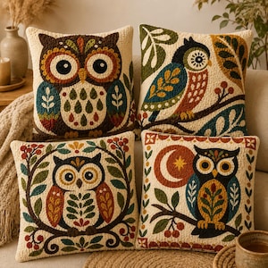 May include: Four square throw pillows featuring textured punch needle embroidery of owls. Each pillow displays a unique owl design in earthy tones of brown, green, blue, and orange, accented with botanical motifs, berries, and a crescent moon.