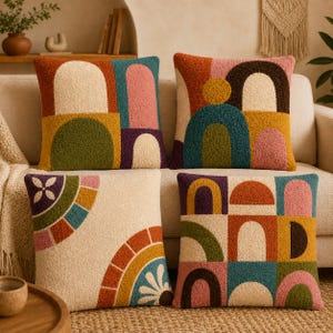 May include: Four square scatter cushions featuring textured, tufted surfaces with geometric patterns. The designs include arches, semicircles, and floral motifs in a palette of mustard yellow, terracotta, sage green, teal, pink, and deep purple.