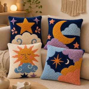 May include: Four square throw pillows featuring textured punch needle designs. One shows a yellow star and clouds on navy, another a yellow crescent moon and clouds on navy, one a sun face on cream, and one a star and moon on blue and navy.