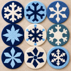 Könnte beinhalten: Ein Set aus neun runden Untersetzern mit verschiedenen Schneeflockenmotiven in Marineblau, Hellblau und Creme. Jeder Untersetzer ist mit einer strukturierten, geschlungenen Garnoberfläche gefertigt und zeigt geometrische Eiskristallmuster.