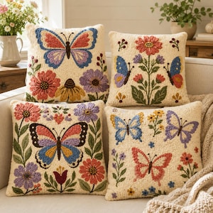 May include: Four square throw pillows with a cream-colored base, each featuring textured punch needle embroidery of colorful butterflies and various flowers in shades of pink, blue, yellow, purple, and green, arranged in a decorative floral pattern.