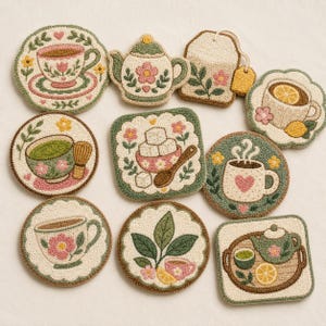 Könnte beinhalten: Eine Sammlung von zehn Punch-Needle-Untersetzern mit verschiedenen Tee-Motiven, darunter Teekannen, Teetassen, ein Teebeutel, Zuckerwürfel und botanische Elemente in den Farben Creme, Salbeigrün, zartem Rosa und Gelb mit texturierten Oberflächen.
