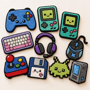 Könnte beinhalten: Eine Sammlung farbenfroher, strukturierter Aufnäher mit Gaming-Motiven. Enthält einen blauen Controller, grüne Handheld-Konsolen, eine Tastatur, Kopfhörer, eine Maus, einen Joystick, eine Diskette, einen pixeligen Alien und einen Computerturm.