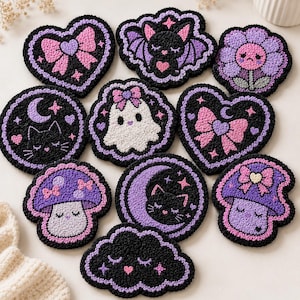 Puede incluir: Una colección de posavasos bordados a mano, en varias formas, incluyendo corazones, murciélagos, flores y setas. Cada posavasos presenta un fondo negro con acentos morados y rosas, y diseños lindos y caprichosos.