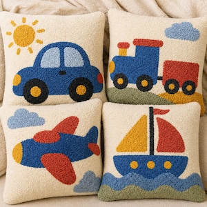 Puede incluir: Un juego de cuatro cojines cuadrados con una base texturizada de color crema. Cada cojín presenta un diseño con relieve: un coche azul con un sol amarillo, un tren azul y rojo, un avión azul y rojo con nubes y un velero azul sobre agua ondulada.