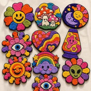 Puede incluir: Una colección de parches bordados coloridos con diseños caprichosos. Los parches presentan una flor sonriente, setas, un sol y una luna, un ojo, un corazón, una lámpara de lava, una nube de arcoíris y una flor alienígena. Cada parche tiene una combinación de colores única y vibrante.