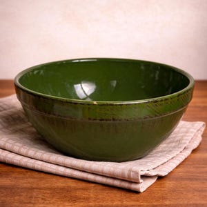 May include: A set of three ceramic nesting bowls in shades of blue, green, and white. The bowls feature a speckled glaze and a simple, modern design. The largest bowl measures approximately 8 inches in diameter.