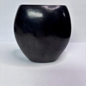 以下が含まれることがあります： 丸みを帯びたボディと広い開口部を持つ、大きな黒いセラミック花瓶。 花瓶は滑らかで光沢のある仕上がりで、シンプルでエレガントなデザインです。 花瓶は家の装飾に適しています。