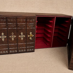 Peut inclure: Un meuble de rangement en bois brun foncé conçu pour ressembler à un ensemble de livres. L'intérieur du meuble est rouge et possède un fermoir doré décoratif. La façade imite un ensemble d'encyclopédies.