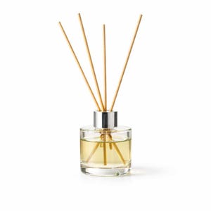 May include: A clear glass aromatherapy diffuser bottle with a silver cap and wooden reeds. The bottle contains a light yellow liquid. The reeds are arranged in a fan shape, extending upwards from the bottle.