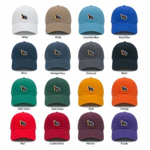 May include: A collection of sixteen baseball caps in various colors including white, khaki, blue, navy, charcoal, black, green, gold, orange, red, maroon, and purple. Each cap features an embroidered graphic of a dog on the front panel.