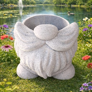 Puede incluir: Una jardinera de gnomo de piedra gris con una gran barba y sombrero, ubicada en un jardín con un estanque y flores en el fondo. La jardinera tiene una superficie texturizada y una abertura ancha.