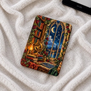 Può includere: Una custodia rettangolare per e-reader con un'illustrazione dettagliata di un interno di biblioteca con una grande finestra ad arco che si affaccia su un cielo notturno con una luna crescente, stelle, librerie, una sfera armillare dorata e viti floreali rosse.