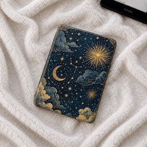 Pode incluir: Uma capa retangular para leitor de e-books com fundo azul-marinho escuro e um padrão celestial de estrelas douradas, uma lua crescente, um sol radiante e nuvens estilizadas. O design cobre a superfície frontal com ilustrações cósmicas.