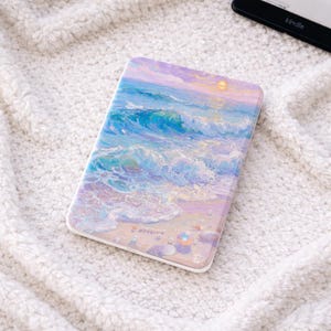 Peut inclure: Un étui rectangulaire avec un motif de vagues océaniques vives. L'œuvre d'art présente des nuances de bleu, de violet et de jaune, représentant une scène de plage avec des vagues déferlantes et un soleil couchant. L'étui est probablement pour un lecteur électronique ou une tablette.