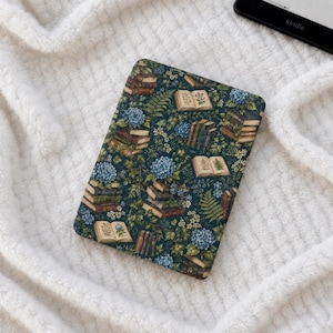 Puede incluir: Una funda rectangular para lector electrónico con fondo verde oscuro y un patrón repetitivo de libros antiguos apilados, racimos de flores de hortensia azules, frondas de helecho verdes y pequeñas flores blancas. Incluye libros abiertos.