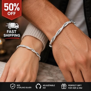 Puede incluir: Dos pulseras de color plateado con un diseño trenzado similar a una cuerda. Cada pulsera se lleva en la muñeca, mostrando un acabado metálico con una textura pulida. Las piezas de joyería son circulares y parecen ser de tamaño ajustable.