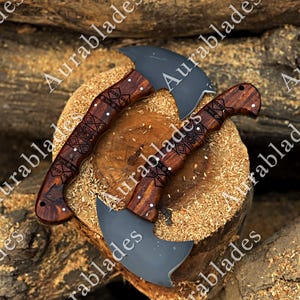 May include: Three axes with dark gray blades and intricately carved wooden handles. The handles feature geometric patterns and are a rich brown color. The axes are displayed on a wooden surface with wood shavings.