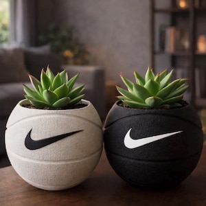 Peut inclure: Deux pots de fleurs sphériques en forme de ballons de basket, l'un blanc avec un swoosh Nike noir et l'autre noir avec un swoosh Nike blanc. Chaque pot contient une plante succulente verte aux feuilles pointues, avec la texture d'un ballon.