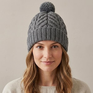 Puede incluir: Gorro gris tejido con trenzas y pompón a juego. El gorro presenta un borde acanalado y un patrón trenzado en la corona. El gorro está hecho de un material suave y cálido, ideal para el clima frío. Un accesorio versátil.