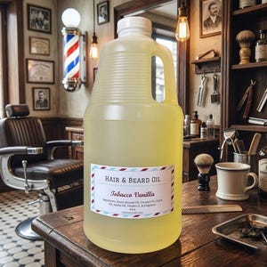 May include: A large, clear plastic jug filled with pale yellow hair and beard oil. The white label features the text Hair & Beard Oil, Tobacco Vanilla, and a list of ingredients including sweet almond oil, coconut oil, castor oil, and jojoba oil.