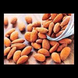 May include: A close-up of a bowl of almonds, with some spilling out onto a wooden surface. The almonds are light brown in color and have a slightly rough texture.