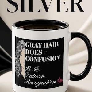 Może przedstawiać: Biały ceramiczny kubek z czarnym wnętrzem i uchwytem. Kubek zawiera tekst "GRAY HAIR DOES = CONFUSION It Is Pattern Recognition" na czarnym prostokącie, z ilustracją kobiety z siwymi włosami. Kubek jest wypełniony ciemnym płynem.