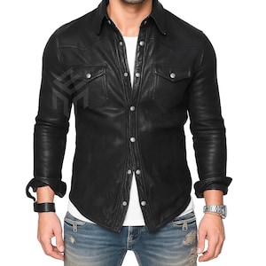 Op de afbeelding: Zwart leren overhemd met een klassieke kraag, twee borstzakken en zilveren knoopsluitingen. Het shirt met lange mouwen wordt over een wit T-shirt gedragen en gecombineerd met een blauwe jeans. De manchetten zijn opgerold.