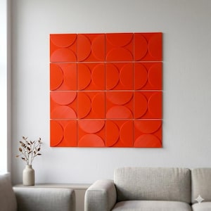 Peut inclure: Une installation murale orange vif présentant un motif répétitif de demi-cercles. L'œuvre d'art est composée de plusieurs carreaux carrés, chacun avec une série de formes courbes, créant un design dynamique et moderne. L'art est monté sur un mur blanc.