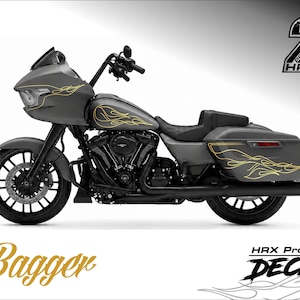 Può includere: Una motocicletta grigio scuro con decalcomanie a fiamma dorata. La motocicletta ha ruote, manubrio e componenti del motore neri. La parola "Bagger" è in corsivo dorato in basso, con "HAX Project Decal" sotto.
