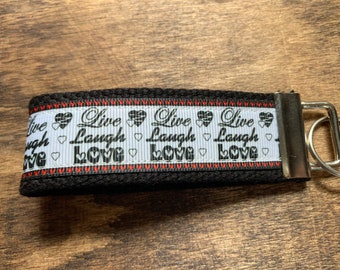 May include: Black key chain with a white ribbon that says "Live Laugh Love" with red hearts and a silver key ring.