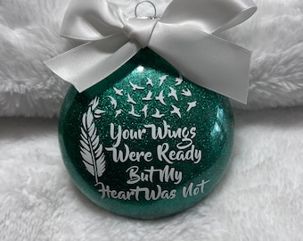 May include: A green glitter Christmas ornament with white glitter birds and a white feather. The ornament has the text "Your Wings Were Ready But My Heart Was Not" on it.