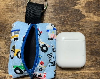 Könnte beinhalten: Eine blaue und weiße Stofftasche mit Reißverschluss und einem schwarzen Band. Die Tasche hat einen Aufdruck von Comic-Fahrzeugen und dem Text "Beep!" Die Tasche ist offen und ein weißes AirPod-Case liegt daneben.