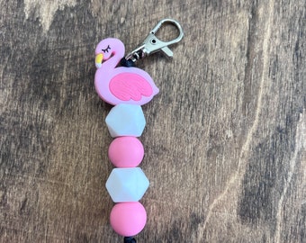 May include: Pink flamingo keychain with a silver clip and a string of pink and white silicone beads.