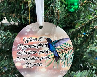 May include: A round, white Christmas ornament with a hummingbird and the text "When a Hummingbird visits your yard, it's a visitor from Heaven".