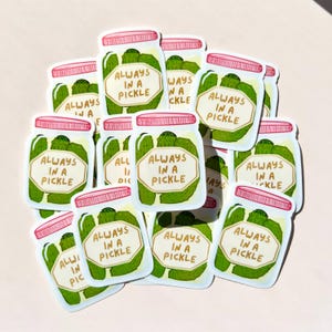 May include: A collection of stickers depicting cartoon jars of pickles. Each jar has a pink lid and a label that reads "ALWAYS IN A PICKLE." The pickles are green, and the jar is clear, with a white background.