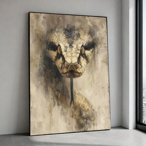 Op de afbeelding: Een ingelijste canvas print met een gedetailleerde schildering van een slangenkop. De slang is geschilderd in beige, bruin en zwart, met gele ogen en een zwarte gespleten tong. Het kunstwerk heeft een textuur, schilderachtige stijl.