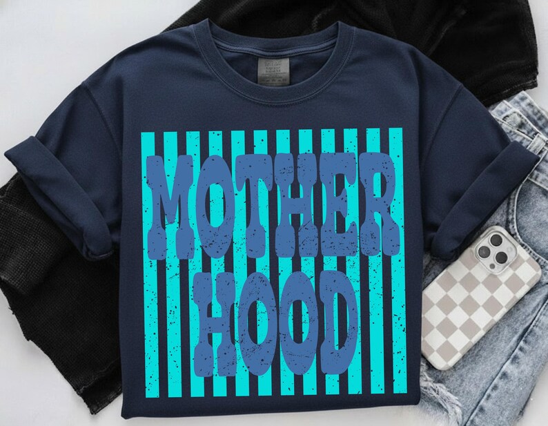 May include: A navy blue t-shirt featuring a graphic design with vertical bright turquoise stripes. The text MOTHER HOOD is printed in a distressed, dark blue, bold font over the stripes. The shirt has a crew neckline and short sleeves.