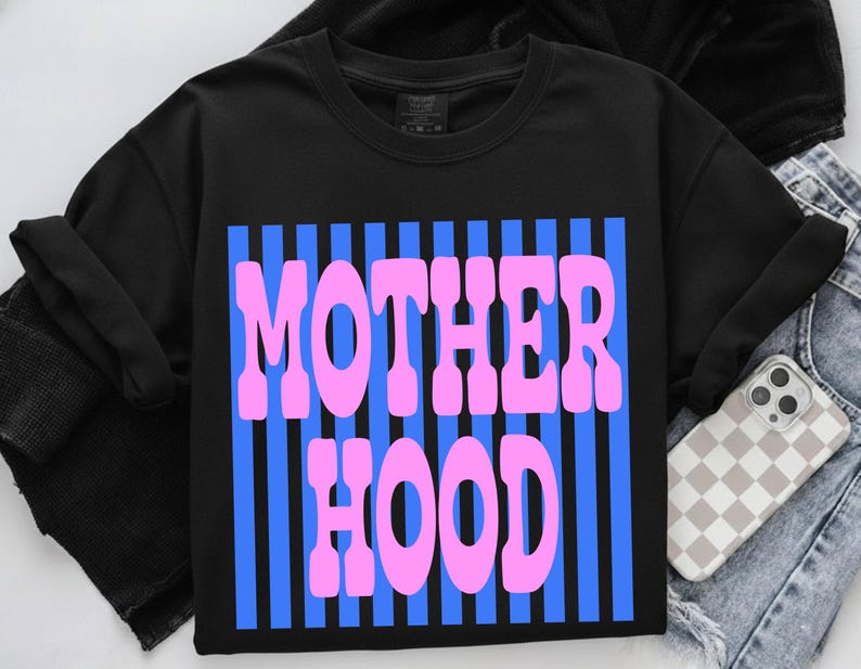 May include: Black crew neck sweatshirt with the word "MOTHERHOOD" in pink bubble letters over blue vertical stripes. The sweatshirt is on a denim background with a phone case.