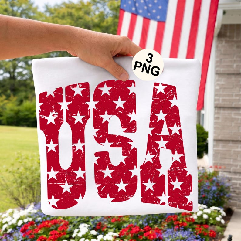May include: White rectangular sign with the word "USA" in distressed red letters filled with white stars. The sign is held up in front of an American flag and a flower bed.
