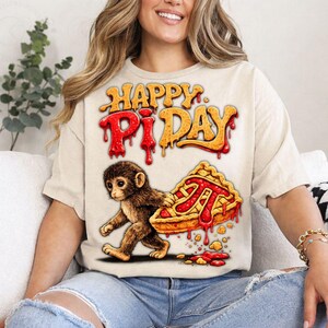 May include: Beige t-shirt with the text "HAPPY PI DAY" in orange and red dripping letters. A cartoon monkey carries a slice of pie with the pi symbol. The pie has a red filling and a golden crust.