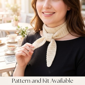 Könnte beinhalten: Ein cremefarbener, gehäkelter Halsschal, der mit einem einfachen Knoten um den Hals gebunden ist. Eine kleine weiße Karte zeigt den Text: Sophie Scarf, Crochet Pattern, Easy Neck Scarf for Beginners. Der untere Text lautet: Pattern and Kit Available.