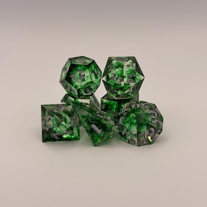 May include: A set of seven polyhedral dice for tabletop games. The dice are transparent with a green, marbled effect and silver numbering. Includes a d4, d6, d8, d10, d12, d20, and a percentile die.