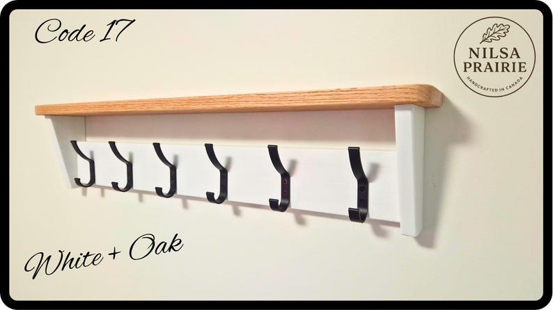 May include: A wall-mounted coat rack featuring a natural oak wood shelf top, a white horizontal backboard, and six black metal hooks. The text Code 17 is in the top left, and a circular logo for NILSA PRAIRIE is in the top right corner.