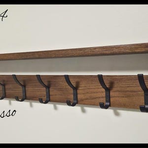 May include: A wall-mounted wooden coat rack with an espresso finish, featuring a top shelf and seven black metal hooks. The text Code 04 and Espresso are printed on the image, along with a circular logo reading NILSA PRAIRIE HANDMADE CANADA.