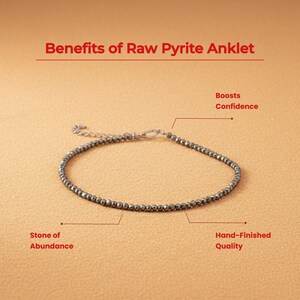 May include: A pyrite ankle bracelet with a silver clasp. The image includes text that reads "Benefits of Raw Pyrite Anklet", "Stone of Abundance", "Boosts Confidence", and "Hand-Finished Quality". The bracelet is made of small, round, dark grey beads.