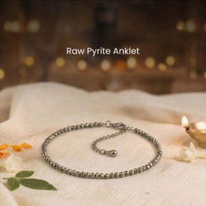 May include: A raw pyrite anklet featuring small, faceted beads. The anklet is silver and has an adjustable chain. The text "Raw Pyrite Anklet" is displayed at the top of the image.